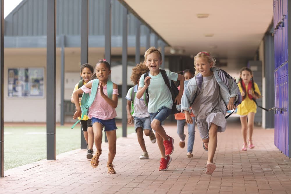 Front,View,Of,Happy,Diverse,School,Kids,Running,In,Corridor